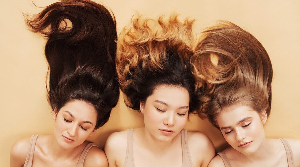 Three women laying on the ground with their hair screeched out above them