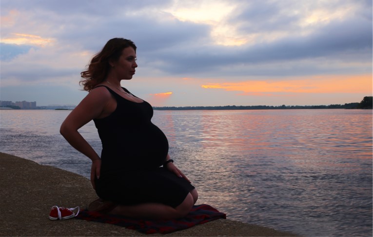 Pregnant person kneeling on beach