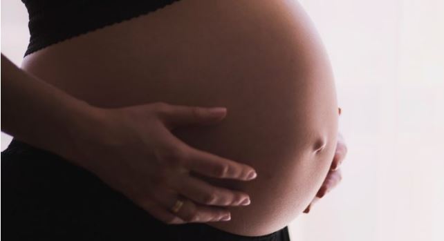 Person with hands on their pregnant belly