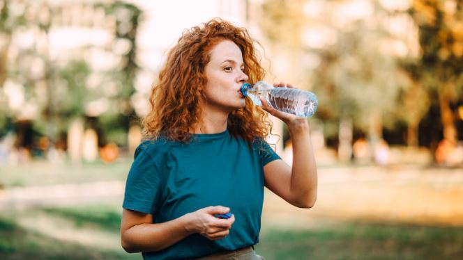 Woman drinking from plastic water bottle