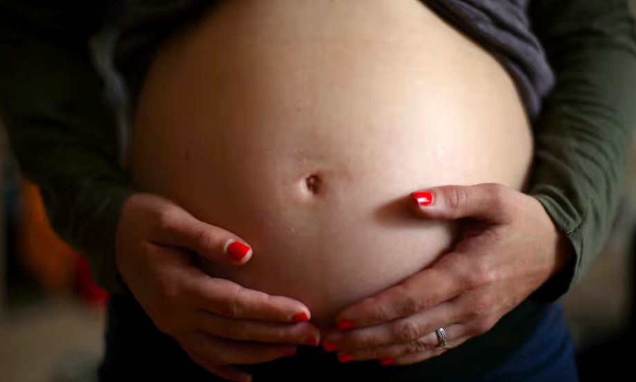 Person with hands on their pregnant belly