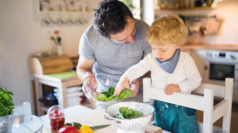 Man with child preparing salad