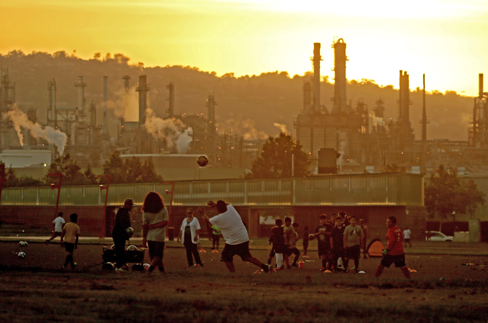 Kids playing soccer next to factory