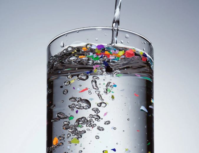 Water glass with plastic particles floating