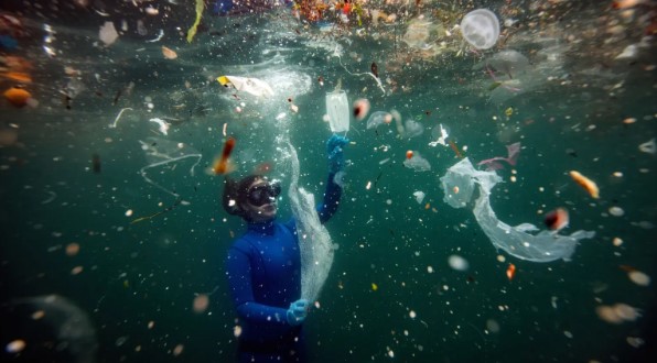 Ocean diver among trash floating in water