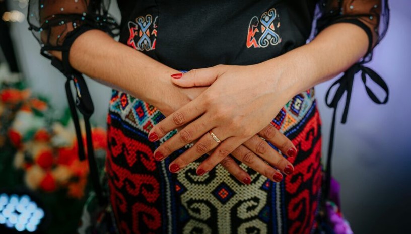 Person's hands crossed over pregnant belly