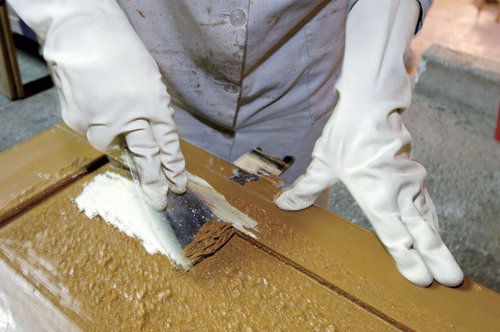 Worker scraping paint off a door