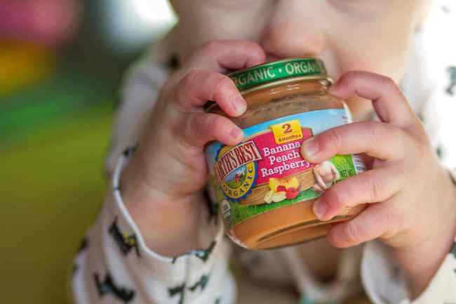 Baby holding a jar of baby food