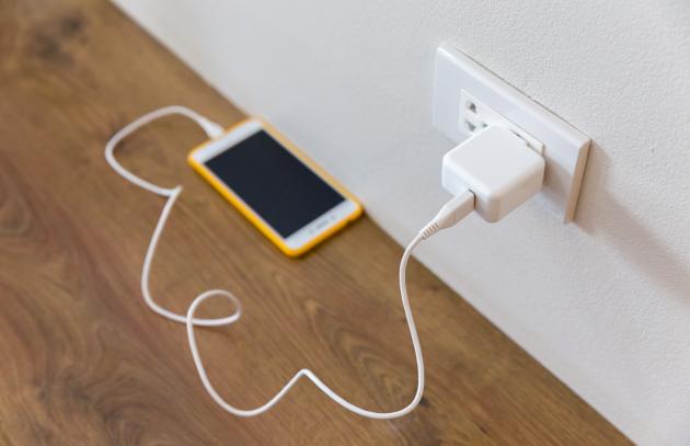 Cell phone on floor connected to wall charger