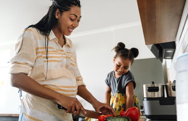 Pregnant mom cooking while child watches