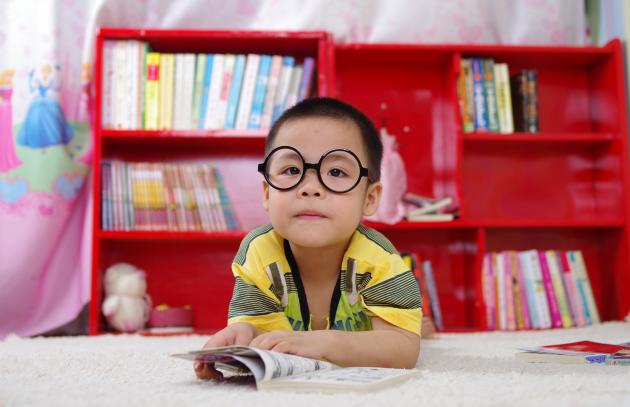 Child wearing glasses reading a book