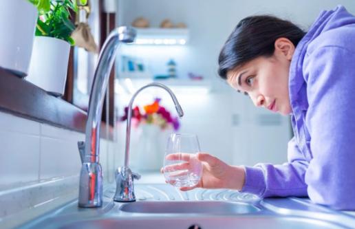 Person filling up glass with tap water from faucet