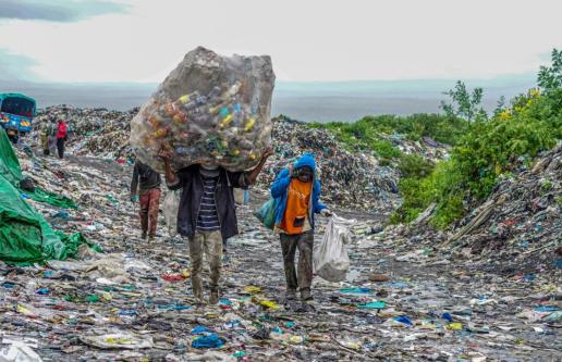 Workers carry giant bags of plastic across sorting plant