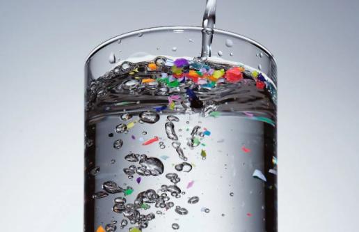 Water glass with plastic particles floating