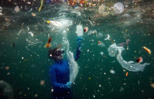 Ocean diver among trash floating in water