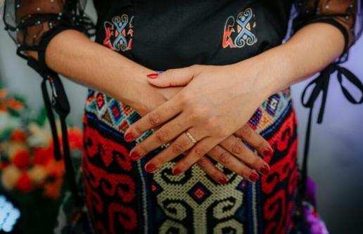Person's hands crossed over pregnant belly