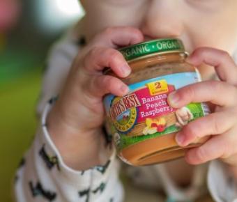 Baby holding a jar of baby food