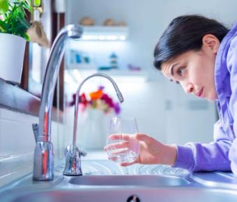 Person filling up glass with tap water from faucet