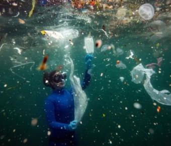 Ocean diver among trash floating in water