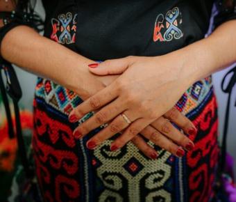 Person's hands crossed over pregnant belly