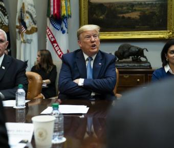 Donald Trump sitting at a table with his arms crossed