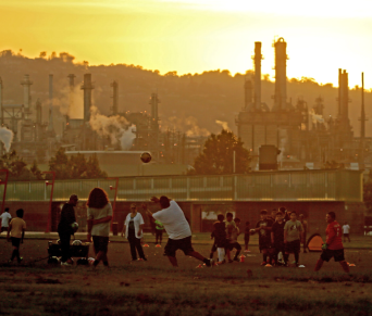 Kids playing soccer next to factory